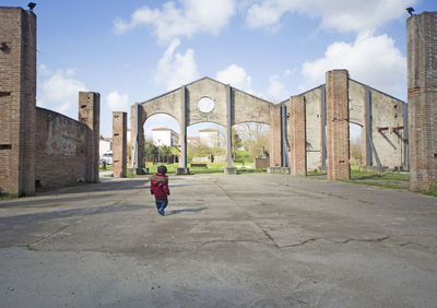 Rear view of baby boy walking on road against sky