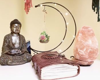 Close-up of buddha statue on table against wall