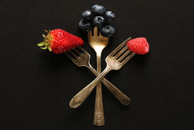 Directly above shot of fruits in container on table against black background