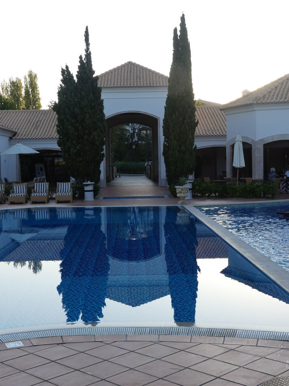 REFLECTION OF TREES AND SWIMMING POOL IN LAKE AGAINST BUILDING