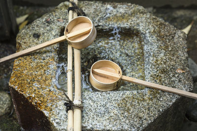 Close view on a japanese temizuya, a purification font, with two bamboo ladles and stone basin.