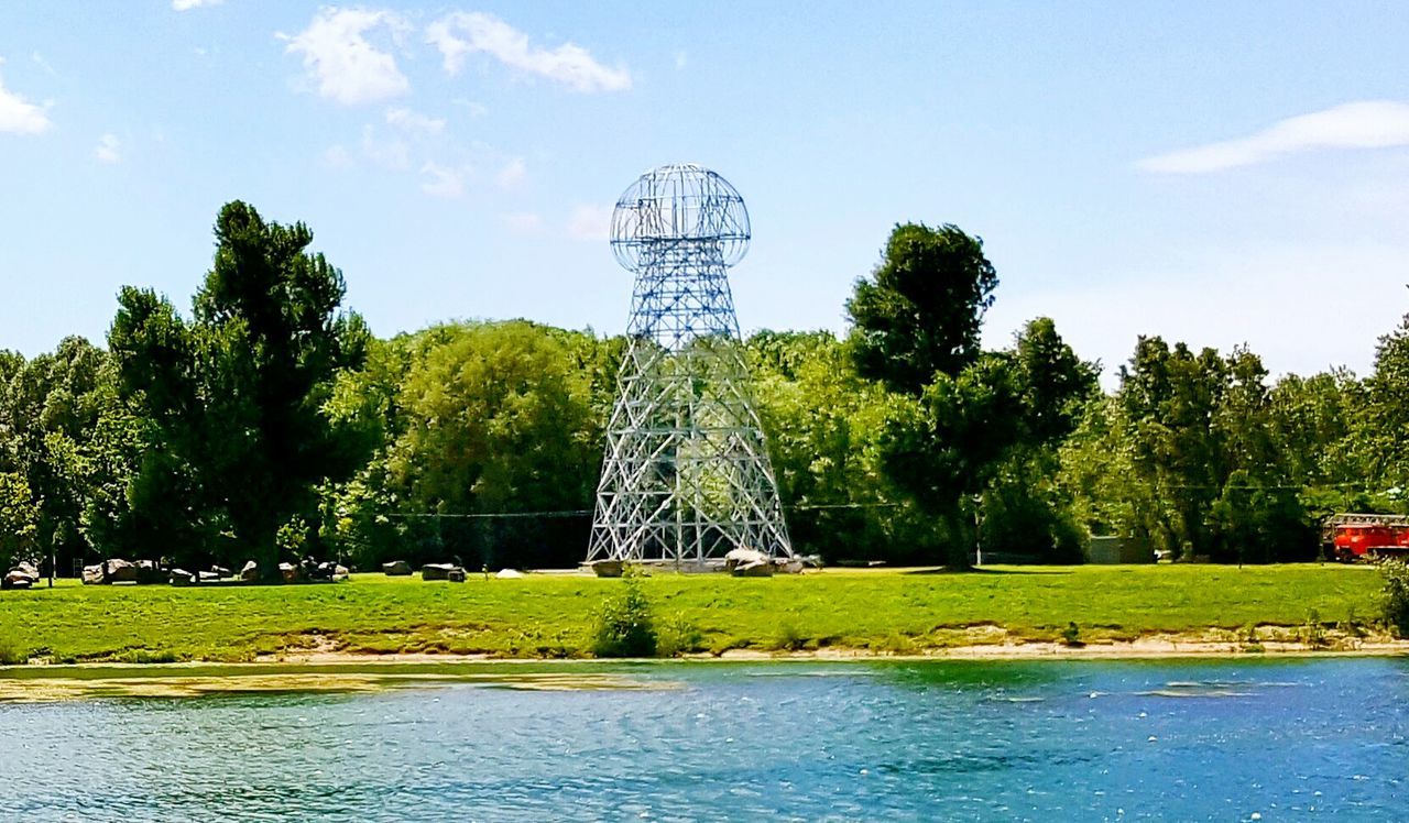 tree, water, green color, waterfront, growth, sky, nature, tranquility, tranquil scene, scenics, fuel and power generation, lake, day, beauty in nature, lush foliage, river, plant, green, built structure, outdoors