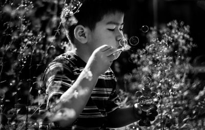 Boy blowing bubbles amidst plants