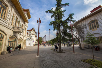 People on street amidst buildings against sky in city