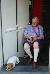 Portrait of an old man with glasses and a dog. he has scars and is dressed with style. 