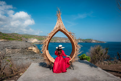 Female tourist sitting on a large bird nest at billabong, bali island, indonesia