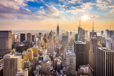 Modern buildings in city against sky during sunset