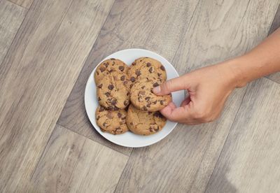 High angle view of hand holding cookies on table