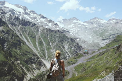 Woman sitting on mountain against sky