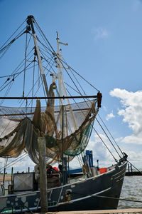 Sailboat moored at harbor against sky