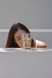 Portrait of young woman drinking glass on table