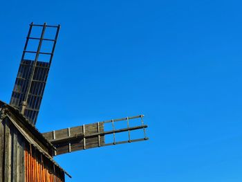 Low angle view of crane against clear blue sky