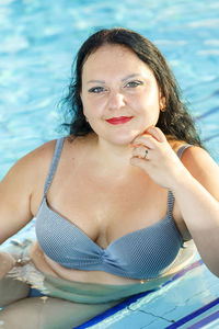 Smiling woman in swimsuit by the hotel pool. vertical photo