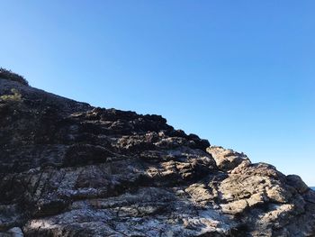 Low angle view of rock formation against clear blue sky