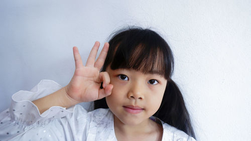 Portrait of girl gesturing against wall