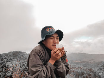 Portrait of man holding ice cream against mountains