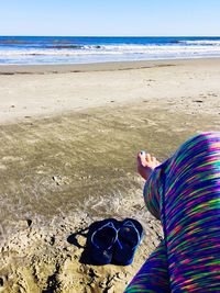 Low section of person on beach against sky