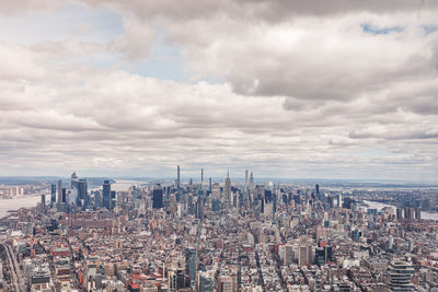 Aerial view of cityscape against cloudy sky