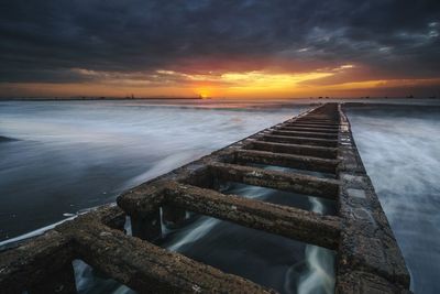 Pier over sea against sky during sunset