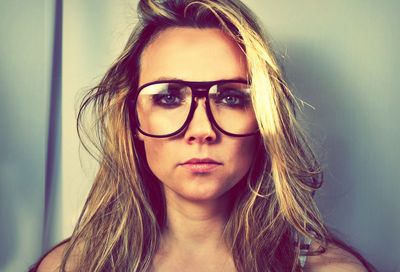 Portrait of blond woman with retro eyeglasses against wall