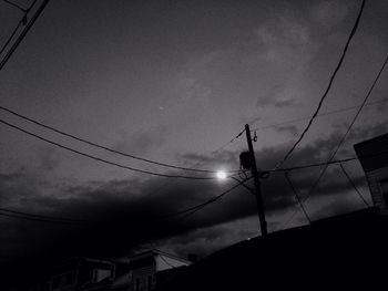 Low angle view of silhouette birds on cable against sky