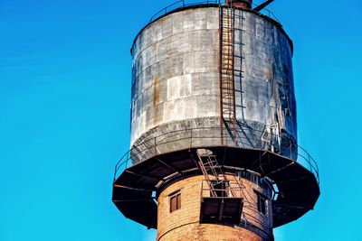 Low angle view of water tower against clear blue sky