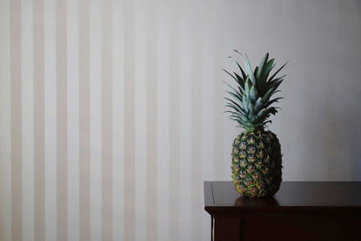 Close-up of pineapple on table against wall at home