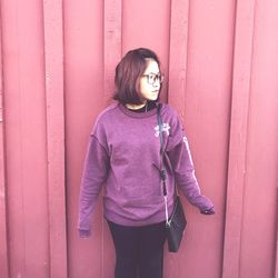 Young woman standing against wall