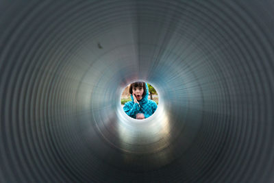 Portrait of cute girl seen through metallic pipe