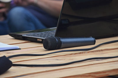 Close-up of microphone by laptop on wooden table