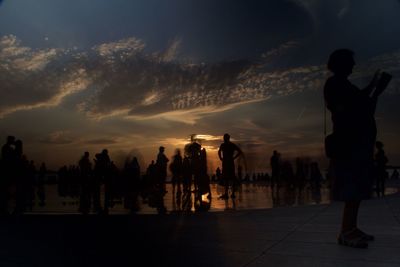 Rear view of silhouette people standing against sky during sunset