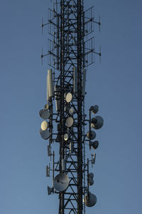 Low angle view of electricity pylon against clear blue sky