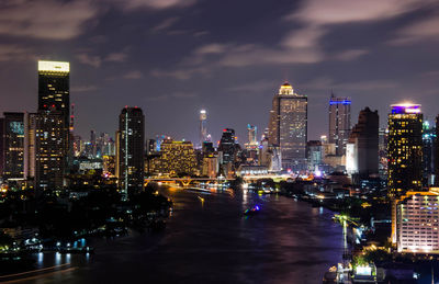 Illuminated buildings in city against sky at night