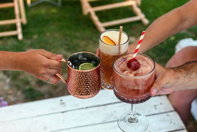 Close-up photo of group of friends clinking cocktail glasses in a bar outdoor.