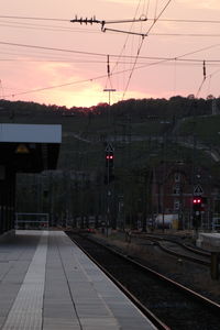 Railroad station platform against sky at sunset