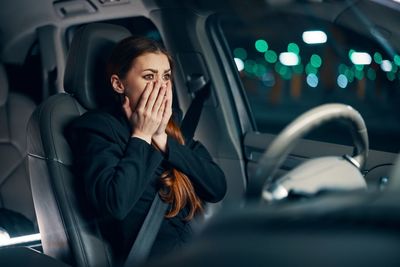 Young woman using mobile phone in car