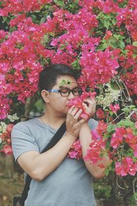 Young man smelling pink flowering plants