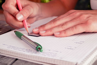 Cropped image of woman drawing line on paper using ruler and pencil