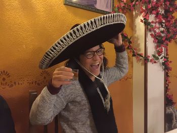 Portrait of happy woman in sombrero hat holding drink at restaurant