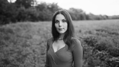 Portrait of young woman standing against trees