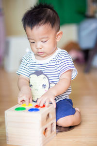 Cute boy playing with toy on floor