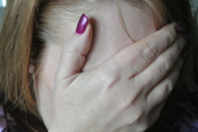 Close-up of shy woman covering face with hand