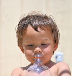 Close-up of cute shirtless boy holding bottle