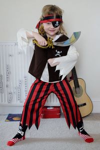 Full length portrait of girl in pirate costume standing at home