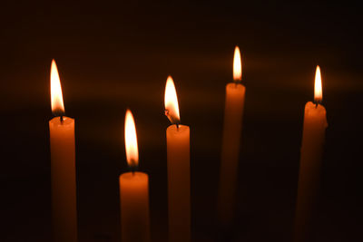 Close-up of lit candles in darkroom