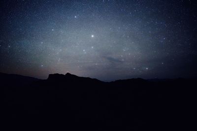 Silhouette mountains against sky at night