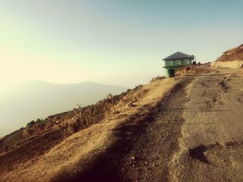 Footpath leading towards mountain against clear sky