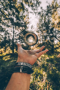 Low angle view of hand holding umbrella against trees