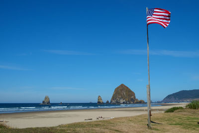 Flag on beach against blue sky