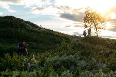 People by plants on land against sky